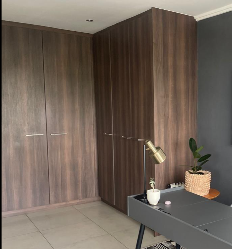 Dark walnut wood-grain built-in corner wardrobe with gold hardware, Durban