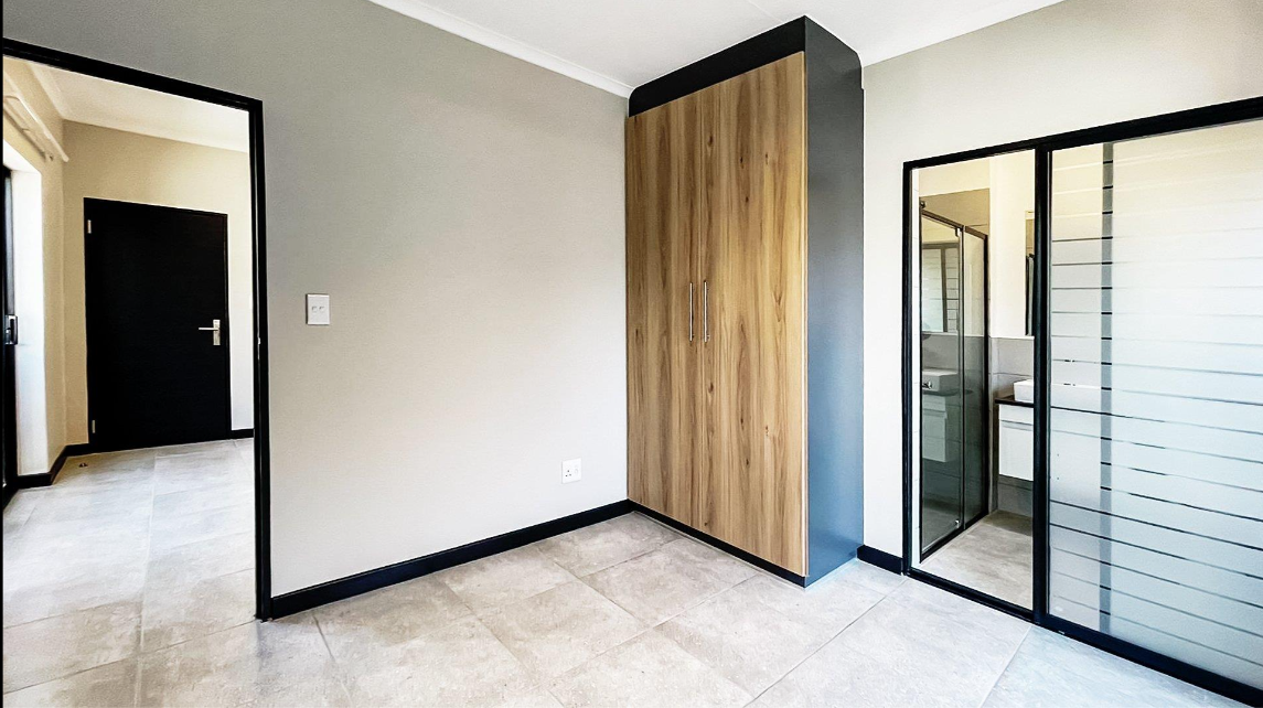 Light oak built-in wardrobe with black frame detail next to mirrored door, Durban