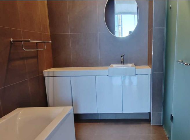 White floor-standing bathroom vanity cupboards with bath and circular mirror, Durban